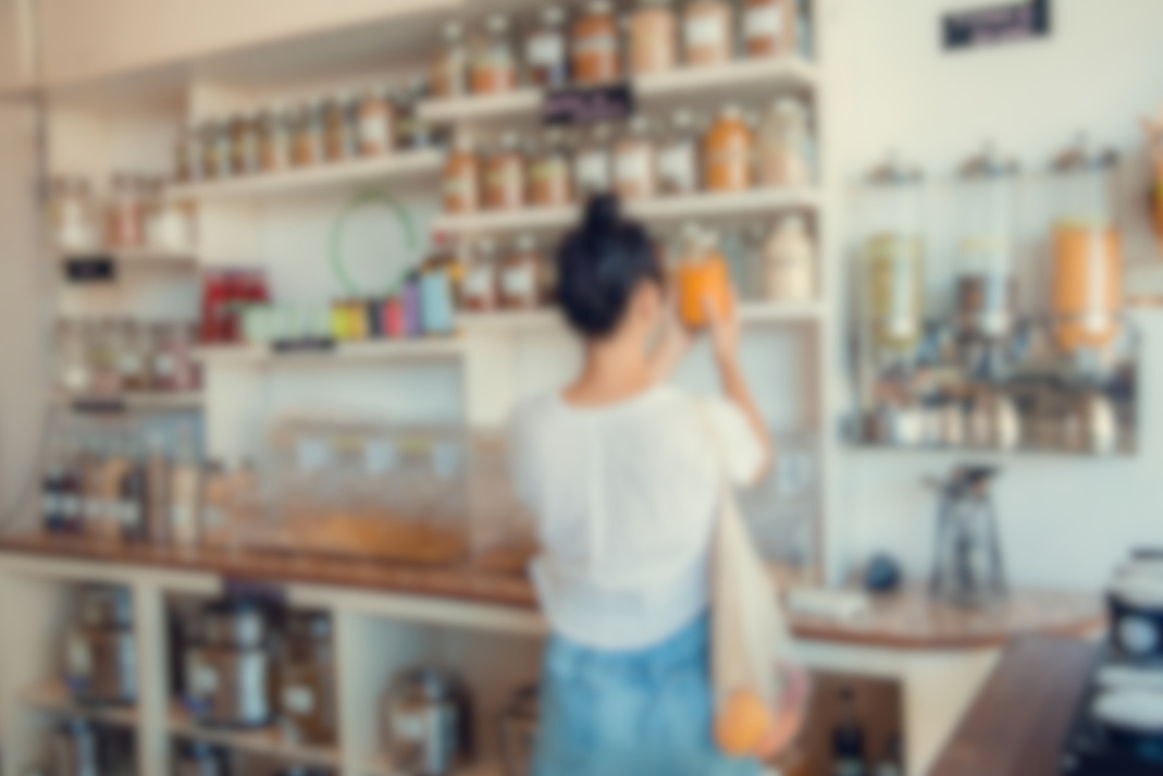 Young woman shopping in zero waste plastic free store with reusable mesh bag. Low waste lifestyle. Sustainable eco lifestyle